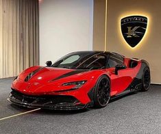 a red sports car is parked in front of a wall with a logo on it