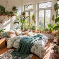 a bedroom with lots of plants in the window sill and on the bed is a blanket