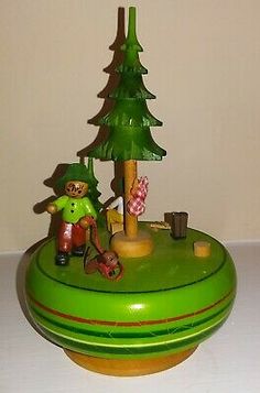 a green toy with a small tree on top and people in the middle sitting around it