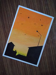 an orange and yellow sunset with birds flying over rooftops on a wooden table top