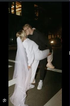 a man and woman kissing in the middle of a crosswalk at night with their arms around each other