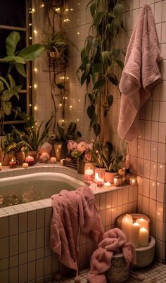 a bathroom with candles and towels on the bathtub next to a tub filled with plants