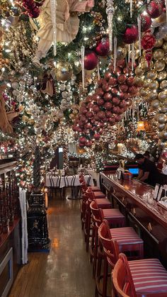 the interior of a restaurant decorated with christmas decorations and ornaments hanging from the ceiling, along with red chairs