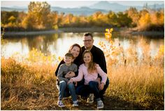 a family poses for a photo in front of a lake