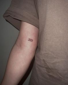 a person with a small tattoo on their arm that reads 22 / 23 in cursive writing