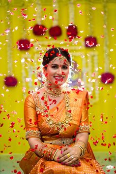 a woman in an orange dress sitting on the ground with confetti falling around her