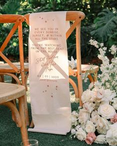 a chair with a sign on it sitting next to flowers and chairs in the grass