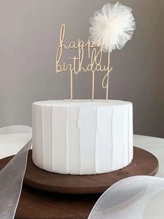 a white cake topped with a wooden happy birthday sign