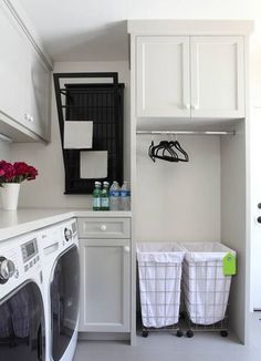 a washer and dryer in a white laundry room with flowers on the counter