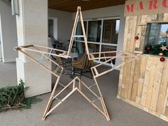 a large wooden star sitting on top of a patio next to a christmas tree in front of a building