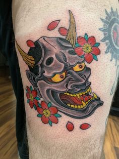 a man with a tattoo on his leg that has an image of a demon and flowers