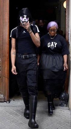 a man and woman dressed in black are walking out of a building with their cell phones