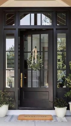 a black front door with two potted plants