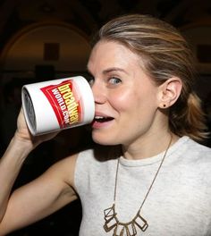 a woman is drinking from a can