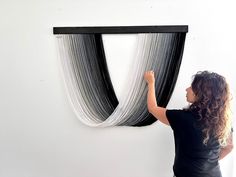 a woman is painting on the wall with black and white lines in front of her