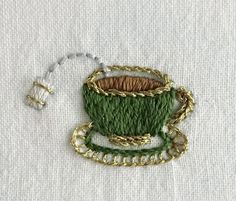 a piece of fabric with some gold chains around it and a green cup in the middle