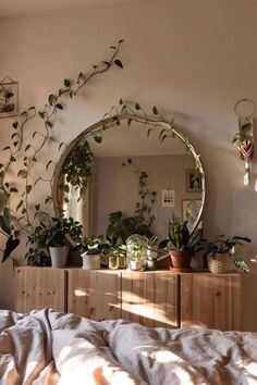 a bedroom with plants on the wall and a mirror above it that is reflecting sunlight