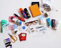 an assortment of personal care items laid out on top of a white surface, including eyeglasses, toothpaste, and more