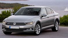 a silver car is parked on the side of the road near some water and trees