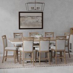 a dining room table with white chairs and a painting on the wall in the background