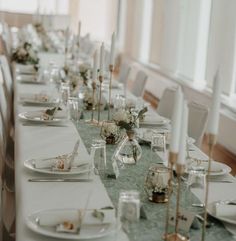 a long table set with white plates and silverware