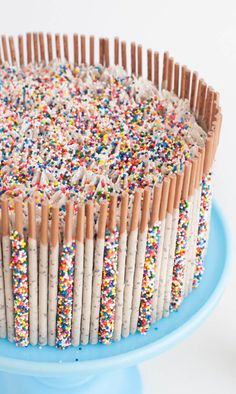 a cake with sprinkles and wooden sticks on the top is sitting on a blue plate