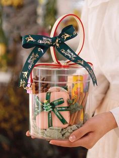 a person holding a clear container filled with assorted candies and other holiday treats