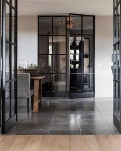 an open glass door leading to a kitchen and dining area with wooden flooring in front of it