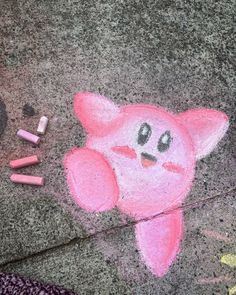 a pink cat drawn on the ground next to some crayons