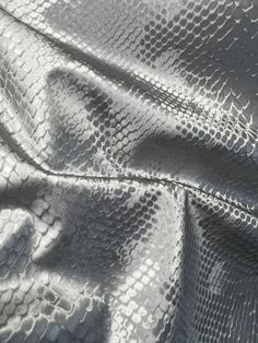 an up close shot of silver fabric with white snakeskind on the side and black spots