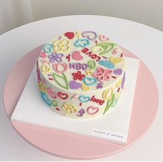 a decorated birthday cake sitting on top of a white tablecloth covered plate with pink border