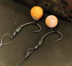 two fishing hooks with eggs on them sitting next to each other in front of a pillow