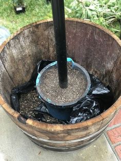 a wooden bucket filled with dirt next to a black pole