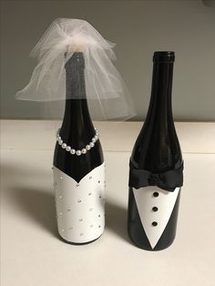 two black and white wine bottles decorated with pearls, tuxedos and a bride's veil