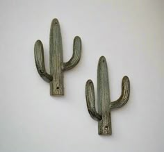 two metal cactus hooks on a white wall