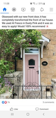 a pink door on the side of a house with an iron fence and flowers around it