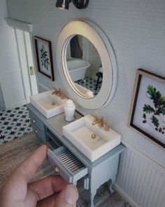 a person taking a photo of a bathroom vanity with two sinks and a mirror on the wall