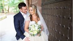 a bride and groom standing next to each other in front of a wooden door with flowers on it