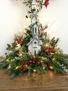 a birdhouse decorated with greenery and lights