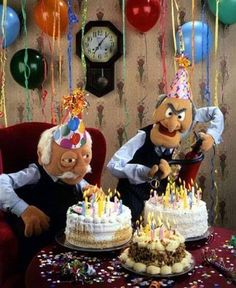 two puppets are sitting in front of a birthday cake