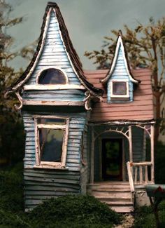 a doll house sitting on top of a lush green field