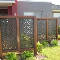 a fence in front of a house with grass and bushes on the side of it