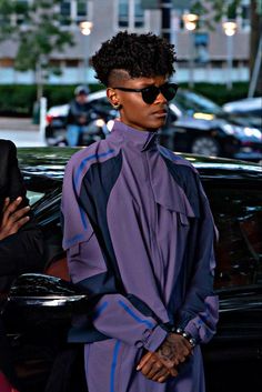 a woman in sunglasses standing next to a car