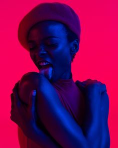 a woman is posing with her hands on her chest in front of a red and blue background