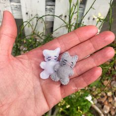 two small stuffed animals sitting on top of someone's hand in front of some flowers