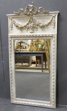 a large white mirror sitting on top of a floor next to a table and chair