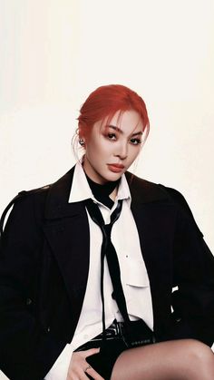 a woman with red hair wearing a black and white shirt and tie sitting on a chair