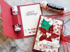 two christmas cards are sitting next to each other on a wooden surface, one has a red ribbon and the other has a green poinsel