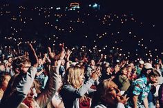 a large group of people standing around each other with their hands up in the air