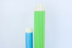 two blue and green toothbrushes sitting next to each other on a white surface